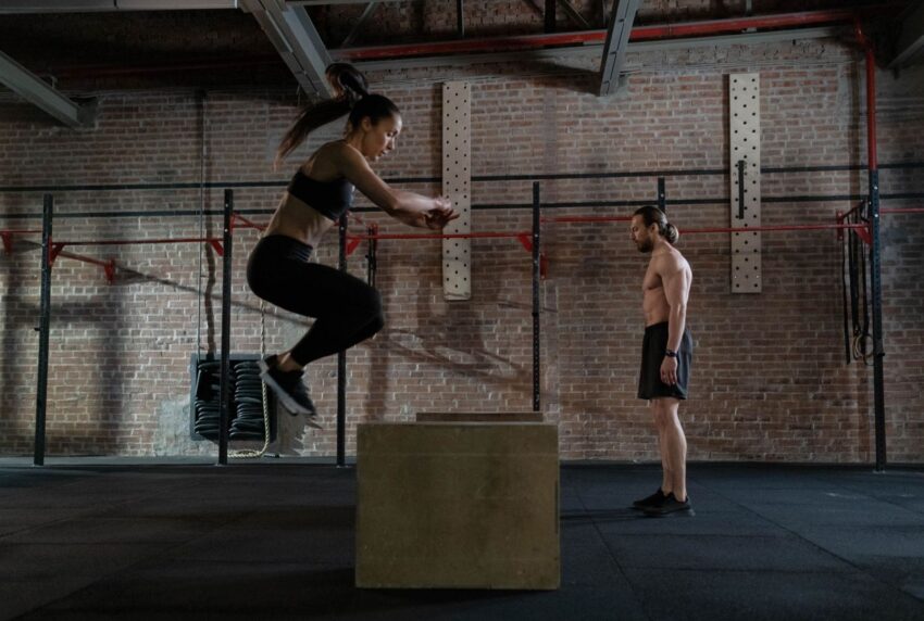 Athletin springt in einer Crossfit-Halle auf eine Holzbox